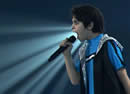 Profile of a boy singing with a beam of light behind him