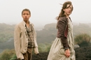 Wide shot of young man and woman in old-fashioned workers clothing stood on a moor