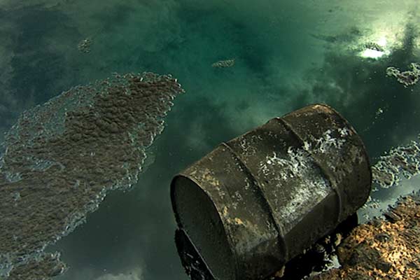 Still image from A Crude Awakening, showing pollution of water from a leaking oil barrel