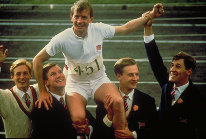 Four young men in matching blazers hold a smiling male runner on their shoulders