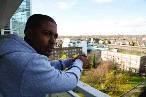 Young man looks over his balcony at a council estate