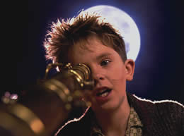 A boy looks down a telescope