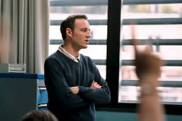 A man stnds next to a window with a raised arm in the foreground