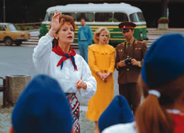Still of a woman trying to get the attention of a group while a soldier and a woman look on holding a camera