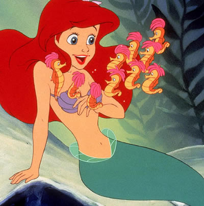 A mermaid sits on the sea-bed surrounded by seahorses.