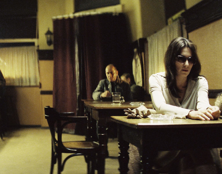 Still from the film, showing Christa-Maria Sieland sat in a cafe, alon. Gerd Wiesler sits on the next table and watches her.