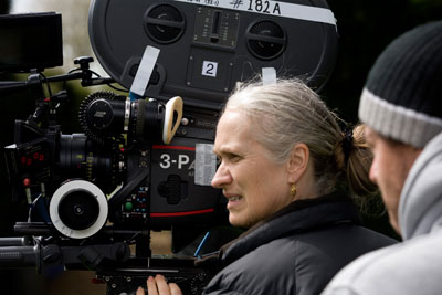 Close-up profile of a woman carefully checking the view through the lens of a full-sized film camera