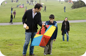 Still image of Amir and his nephew in a park, holding a kiteman flying a kite